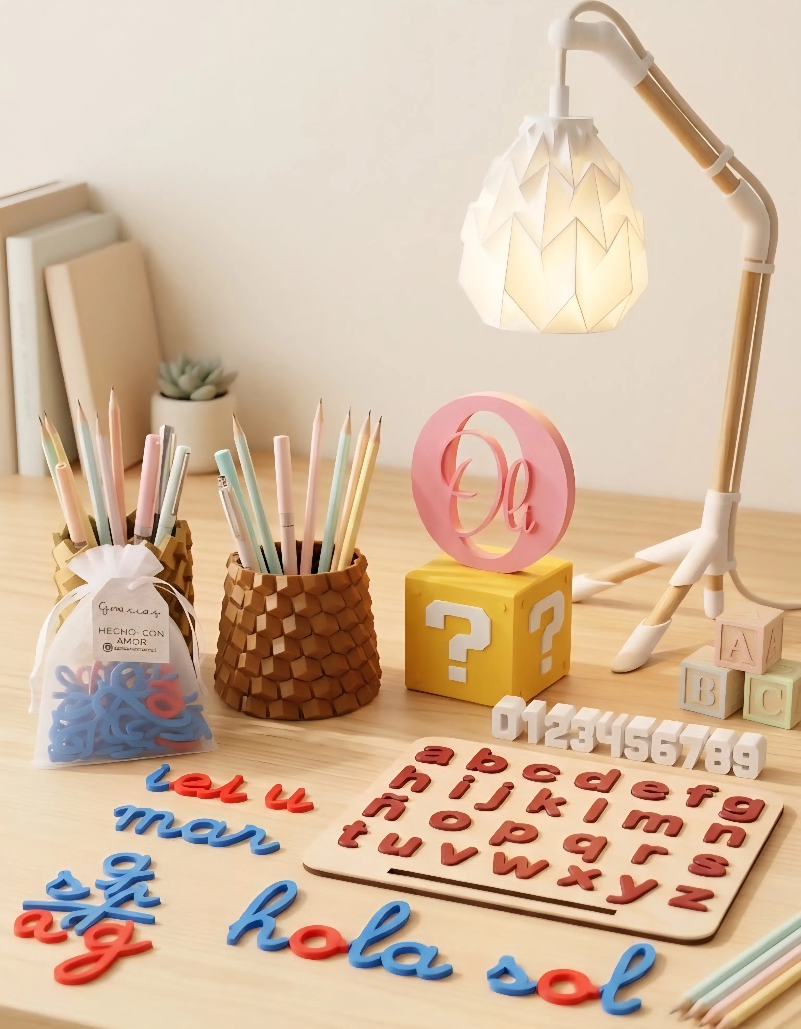 Escritorio con lámpara de origami, lapiceros y letras cursivas educativas